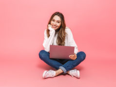 Wirtualna komunikacja – jak zwracać się do innych w internecie? Uśmiechnięta dziewczyna przy komputerze