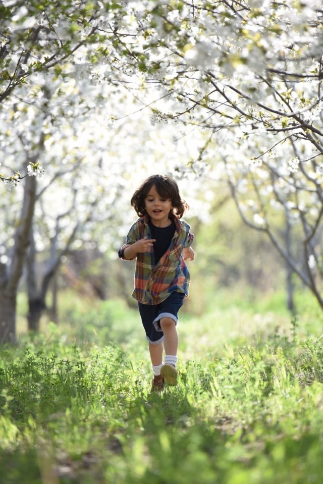 Dziecko w szortach i tshircie biegnące przez wiosenny ogród