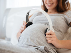 Co słyszy dziecko w brzuchu mamy? Kobieta w ciąży przykładająca słuchawki do brzucha