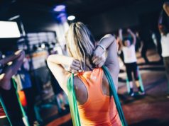 Ćwiczenia z gumami – czy warto? kobieta ćwicząca z bandem oporowym z grupą ludzi