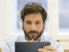 Komfort pracy biurowej, czyli słuchawki do redukcji hałasu i nie tylko młody mężczyzna pracujący na tablecie w słuchawkach