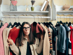 Kapsułowa szafa – jak ją ożywić i jak dobrać dodatki? dziewczyna pomiędzy ubraniami na wieszakach