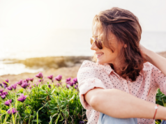 Jaka koszula damska na wiosnę? kobieta w różowej koszuli w groszki na tle kwiatów