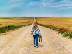 Co spakować na weekend za miastem? Pomysły na modne stylizacje kobieta z walizką idąca wiejską drogą