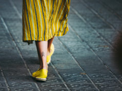 Espadryle i plecione baleriny, czyli modne buty kobiece w tym sezonie zbliżenie na kobiece nogi na ulicy w żółtej spódnicy z żółtymi espadrylami na stopach stylizacja casual