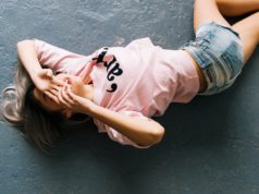 Spodenki damskie – sposób na idealną letnią stylizację kobieta na podłodze w różowej bluzce i szortach