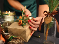Jak znaleźć idealny prezent na święta? Pakowanie świątecznych prezentów. Kobieta pakuje prezent świąteczny