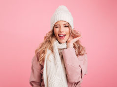 Jakie zabiegi kosmetyczne są najchętniej wybierane zimą? młoda dziewczyna w zimowym stroju na różowym tle