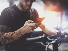 Jakie rozwiązania technologiczne w smartfonach są teraz na topie? Sprawdzamy! wytatuowany mężczyzna ze smartfonem w dłoni