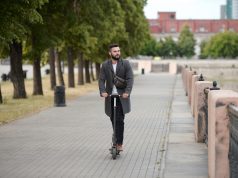 Płaszcze męskie – na jaki rodzaj się zdecydować? mężczyzna w płaszczu na hulajnodze